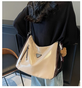 Detailansicht beige Tragetasche aus Ölwachsleder mit Bärenanhänger und Metalllogo-Akzent
