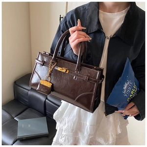 Detail of dark brown retro leather handbag with gold twist lock on a vintage background