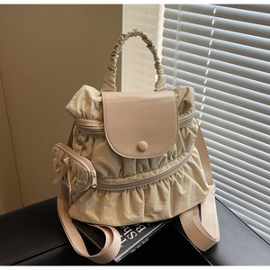 Detail of beige pleated nylon backpack featuring cloud texture and bow coin purse charm