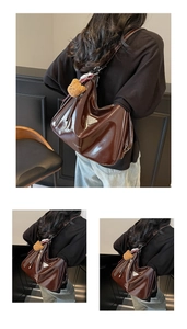 Detail der dunkelbraunen Lackleder-Tasche mit silbernem Metalldreieck und Bärenanhänger