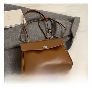 Close-up of brown leather briefcase featuring a silver metal twist lock and flap closure