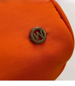 Macro di tessuto nylon ripstop arancione con dettaglio logo metallico circolare lettera W
