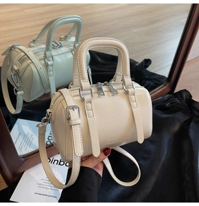 Vue miroir détaillée d'un sac Boston blanc crème avec doubles poignées et détails argent