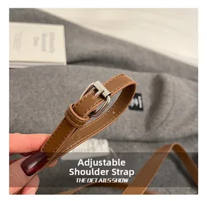 Detail of brown leather adjustable shoulder strap with silver buckle and fine stitching
