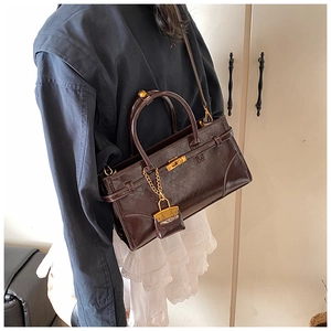 Detail of a dark brown luxury leather handbag with golden clasp and texture closeup