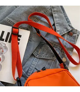 Dettaglio di una borsa a tracolla arancione vivace con ampia tracolla intrecciata su denim