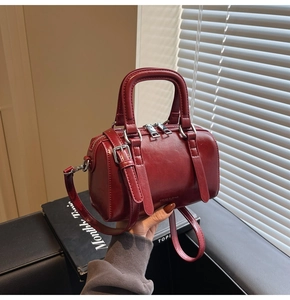 Détails macro d'un sac Boston rouge foncé avec quincaillerie en métal argenté poli