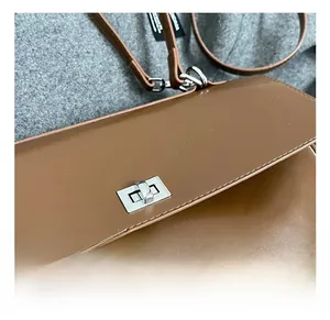 Detail shot of the polished silver rectangular metal twist lock on a brown leather handbag
