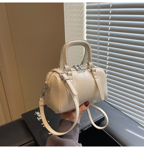 Gros plan du sac Boston en cuir beige avec détails argentés et bandoulière réglable