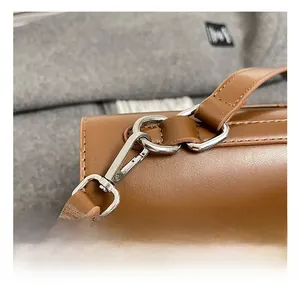 Close-up of silver metal hardware and stitching detail on a brown leather shoulder bag