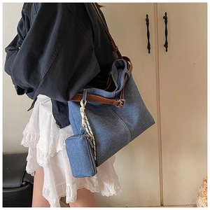Detailed shot of large denim tote bag featuring brown straps and a mini matching coin purse