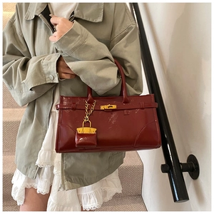 Detailed macro of the vintage burgundy tote bag with gold lock and mini charm
