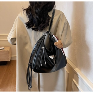 Detail der schwarzen Ölwachs-Ledertasche mit Silberbeschlägen an einem Model im Trenchcoat