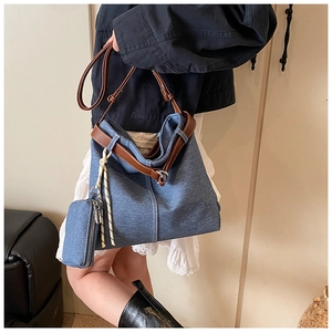 Detail of blue denim tote bag featuring a brown leather strap and small detachable coin purse