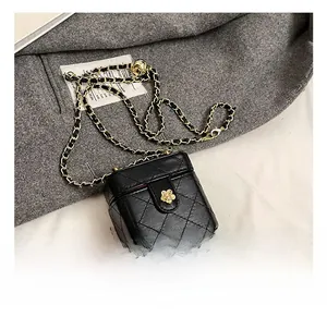 Detail showing black quilted mini bag with golden camellia clasp and chain strap