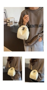 Dettaglio di una mini borsa a tracolla bianco crema con zip nere e logo in metallo
