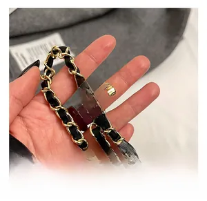 Macro shot of gold metal and black leather chain strap with adjustable gold ball slider