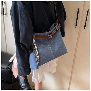 Detail of blue denim tote bag featuring brown leather straps and a mini detachable pouch
