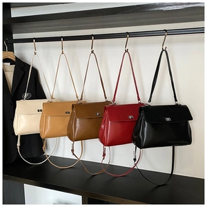 Five minimalist faux leather flap handbags in neutral colors displayed on a rack