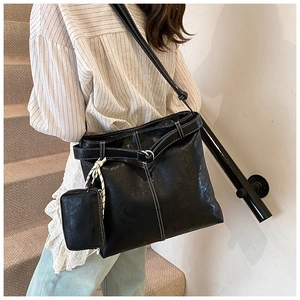 Detail of black faux leather tote bag with white contrast stitching and matching mini pouch