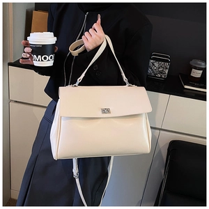 Detailed view of beige faux leather handbag with silver twist lock and sturdy top handle