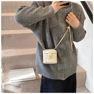 Lifestyle shot of a mini white quilted crossbody bag with gold floral clasp on a chain