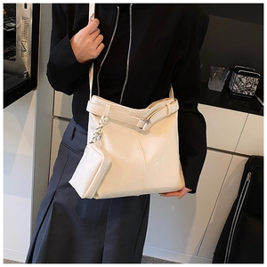 Detail of a large cream-colored faux leather tote bag with a matching small pouch