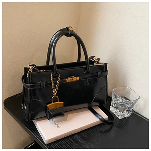 Detail of black glossy leather briefcase with golden metal turn-lock and mini coin purse