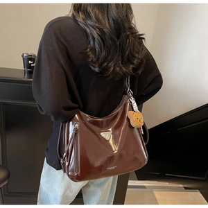Detail der dunkelbraunen Ölwachs-Ledertasche mit silbernem Metalldreieck und Bärenanhänger