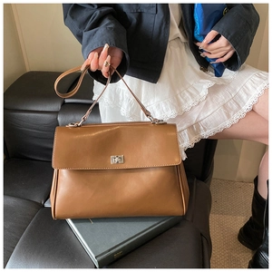 Detailed view of brown briefcase bag with silver metal swivel lock and long strap