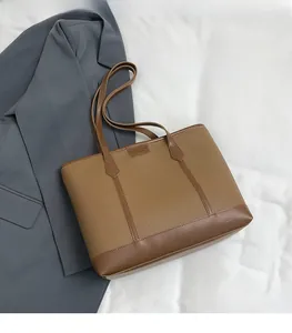 Detalle del bolso tote de cuero marrón con textura lichi y costuras lisas