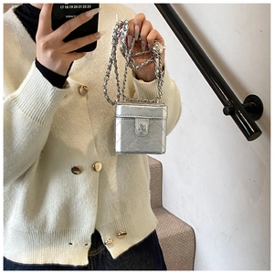 Close-up of a silver quilted mini box bag with flower clasp and metal chain strap