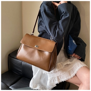 Close-up of brown leather briefcase with silver metal turn-lock and shoulder strap