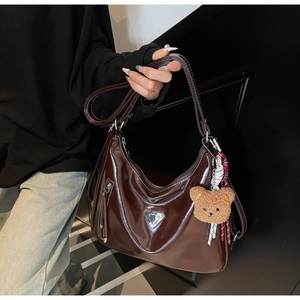 Detail der Vintage Ölwachs Leder-Tote mit Metallplakette und plüschigem Bärenanhänger