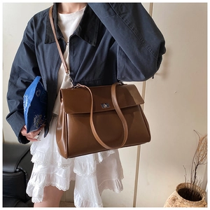 Close-up of a vintage brown leather shoulder bag featuring a metallic twist lock and handle