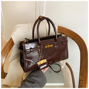 Detail of vintage brown patent leather handbag with gold metal clasp on a wooden chair