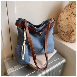 Detail view of large denim tote bag with leather straps and matching zip pouch