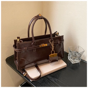 Detail of vintage dark brown tote bag with gold turn-lock and mini charm accessory