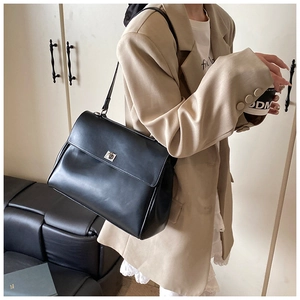Detail showing the silver metal square buckle and black PU leather on a flap bag