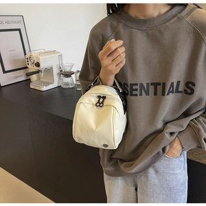 Dettaglio della borsa a mano in tela crema con doppie cerniere e logo in metallo