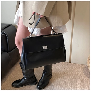 Close-up of matte black leather briefcase with silver twist lock and handle detail