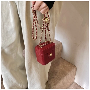 Detail of red quilted mini box bag with golden chain strap and flower clasp