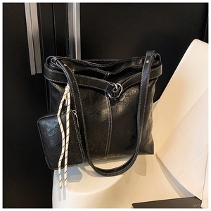 Detail of black tote bag with white contrast stitching and mini attached zipper pouch