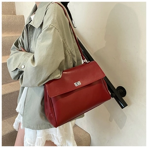 Street style shot of a burgundy matte leather shoulder bag with silver turn-lock clasp