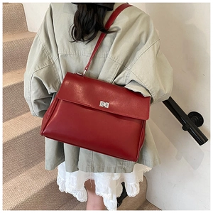 Deep red leather tote bag with silver twist lock shown on a model in a modern staircase setting