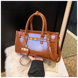 Close-up of brown glossy handbag with golden hardware and mini pouch charm detail