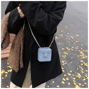 Detailed view of mini blue denim quilted crossbody bag with gold chain and flower clasp