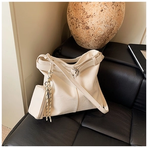 Detail of a large cream leather tote bag with a small matching pouch on a black sofa