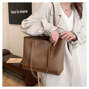 Detalle del bolso tote de cuero caramelo con textura granulada y letras de moda chic