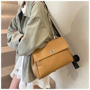 Detail of camel brown faux leather shoulder bag with elegant silver twist-lock closure